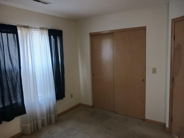 unfurnished bedroom featuring light carpet, baseboards, and a closet