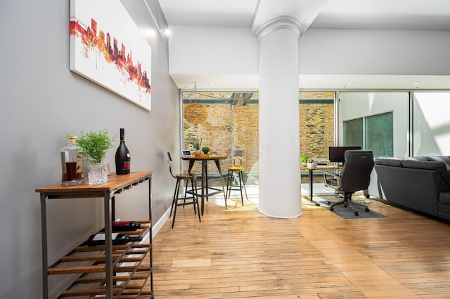 home office featuring light wood-style floors and decorative columns