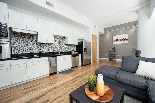 kitchen featuring under cabinet range hood, visible vents, open floor plan, appliances with stainless steel finishes, and dark countertops
