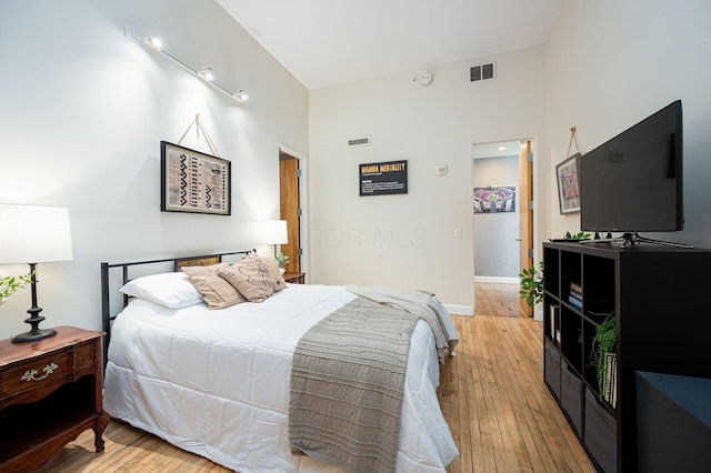 bedroom featuring light wood-style flooring, visible vents, and baseboards