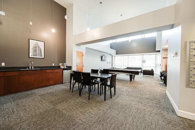 carpeted dining space with baseboards, a sink, and a high ceiling