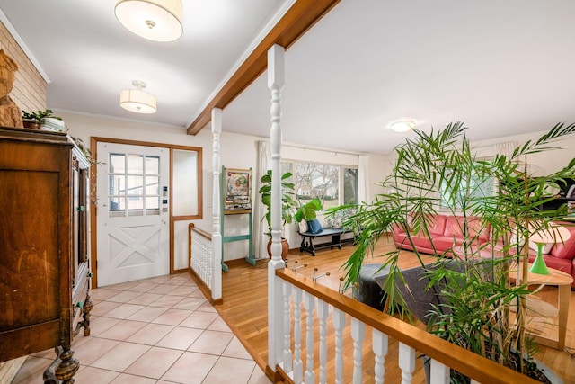 foyer entrance featuring light tile patterned floors, plenty of natural light, beamed ceiling, and crown molding