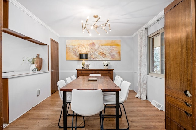 dining area featuring crown molding, visible vents, light wood finished floors, and a chandelier