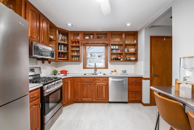 kitchen with a sink, light countertops, brown cabinets, stainless steel appliances, and open shelves