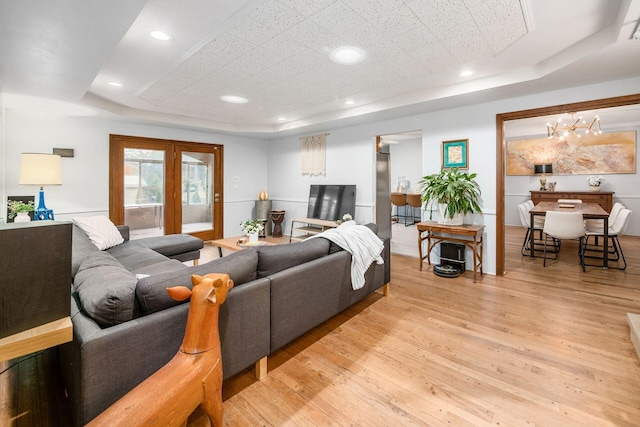 living area featuring recessed lighting, light wood-type flooring, and a tray ceiling