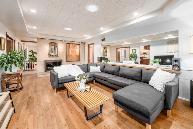 living area with recessed lighting, visible vents, a brick fireplace, and light wood-style flooring