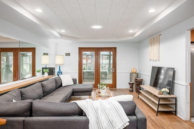 living room featuring recessed lighting, light wood-type flooring, and a raised ceiling