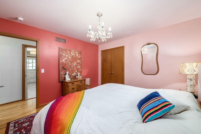 bedroom with visible vents, an inviting chandelier, and wood finished floors