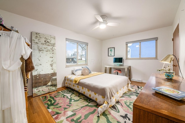 bedroom featuring ceiling fan, visible vents, baseboards, and wood finished floors