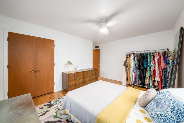 bedroom featuring light wood finished floors, visible vents, baseboards, and a ceiling fan