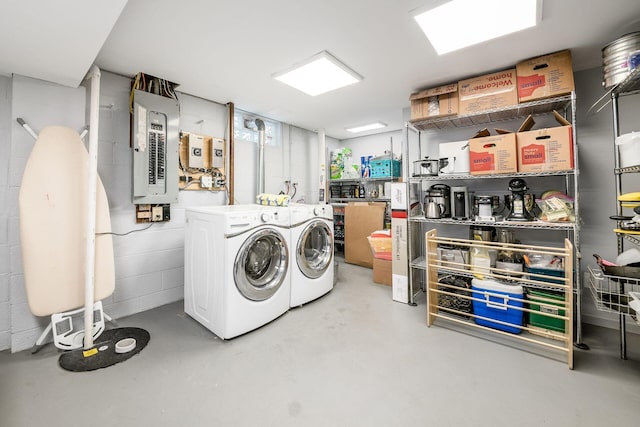 clothes washing area featuring laundry area, concrete block wall, electric panel, and separate washer and dryer