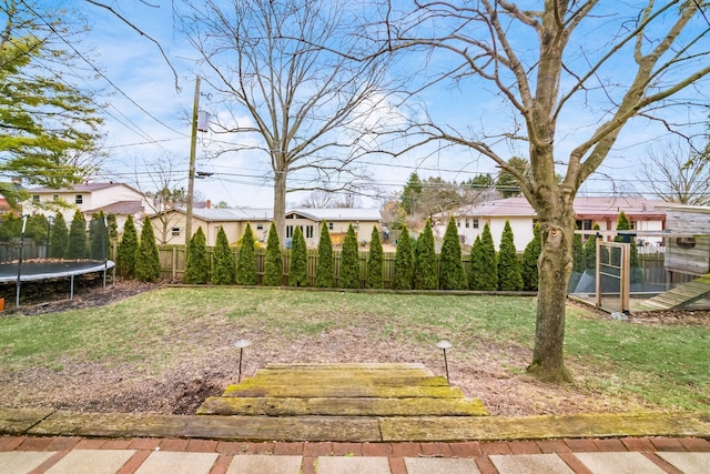 view of yard with a trampoline and fence