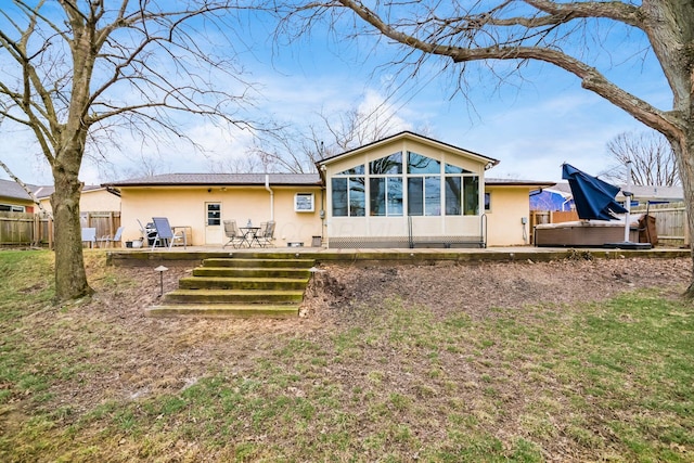 back of house with stucco siding, a deck, and fence