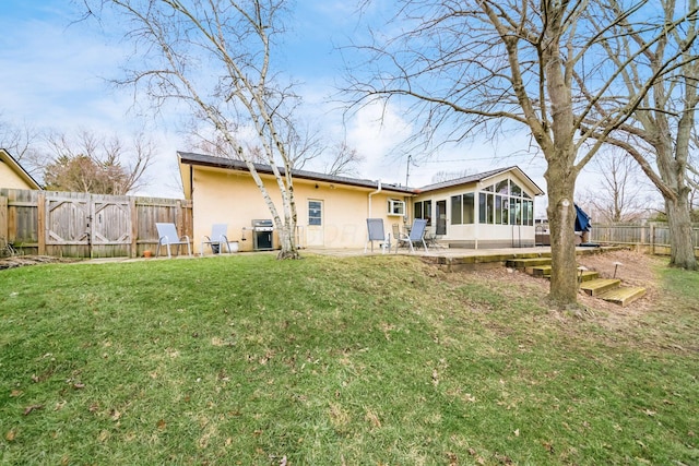 back of house with a patio, a fenced backyard, a sunroom, stucco siding, and a lawn