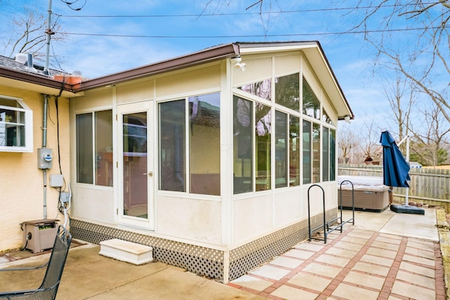 view of side of property featuring a patio area, fence, a sunroom, and stucco siding