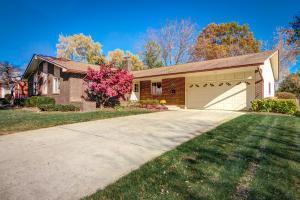 single story home featuring driveway, a front yard, and a garage