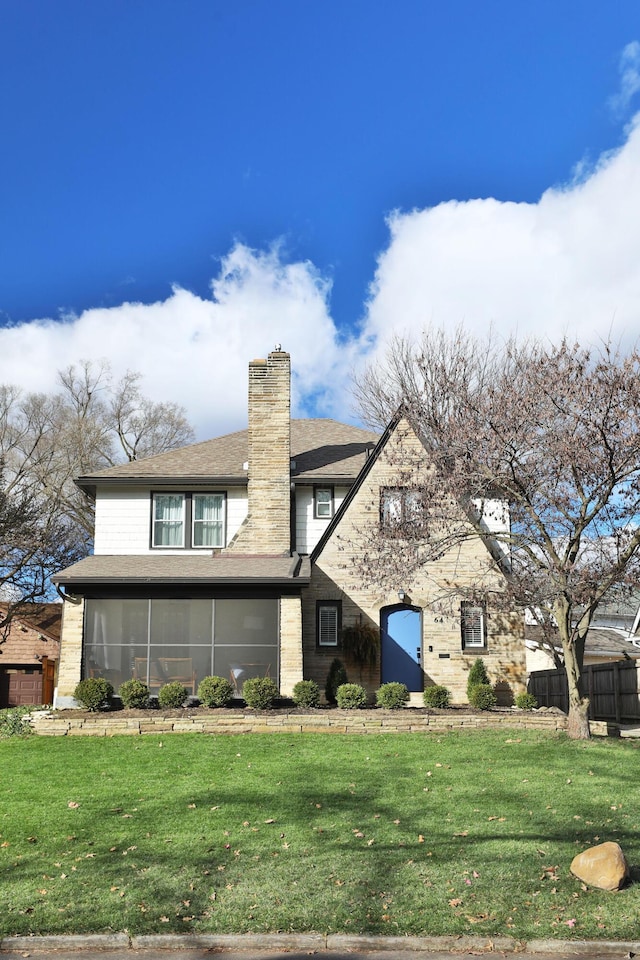 view of front of house featuring a front yard, a sunroom, and a chimney