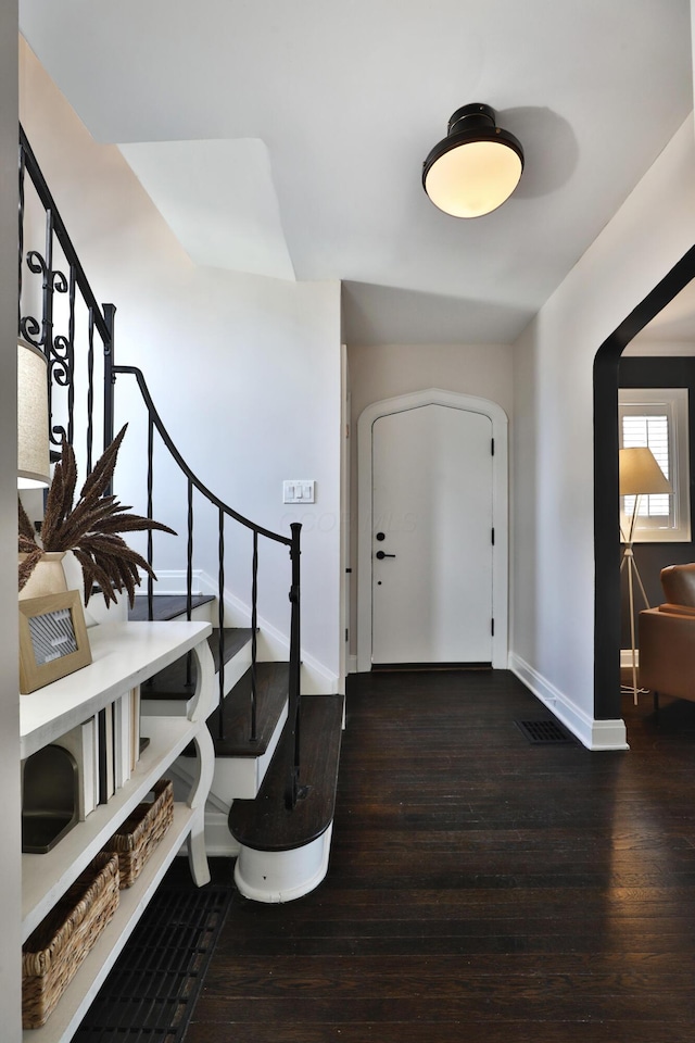 foyer entrance with hardwood / wood-style flooring, baseboards, visible vents, and stairway