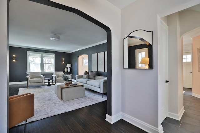 living area with arched walkways, dark wood-style flooring, and baseboards