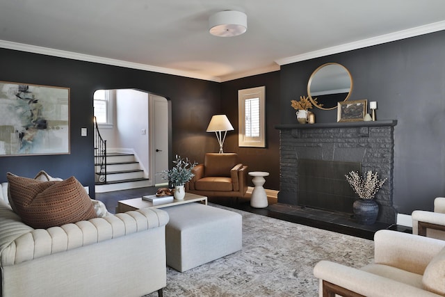 living area with arched walkways, wood finished floors, stairs, crown molding, and a fireplace