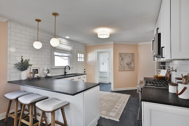 kitchen with dark countertops, a peninsula, white cabinetry, and decorative backsplash