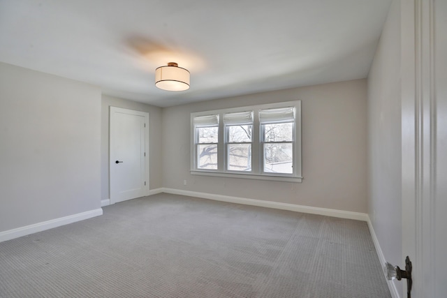 unfurnished room featuring light carpet and baseboards