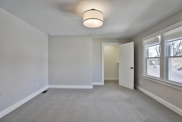 unfurnished room with light colored carpet, visible vents, and baseboards