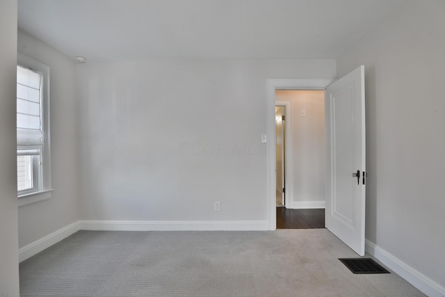 carpeted spare room featuring baseboards and visible vents