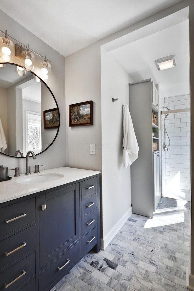 bathroom with a stall shower, baseboards, and vanity