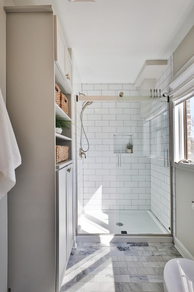 bathroom with marble finish floor and a shower stall