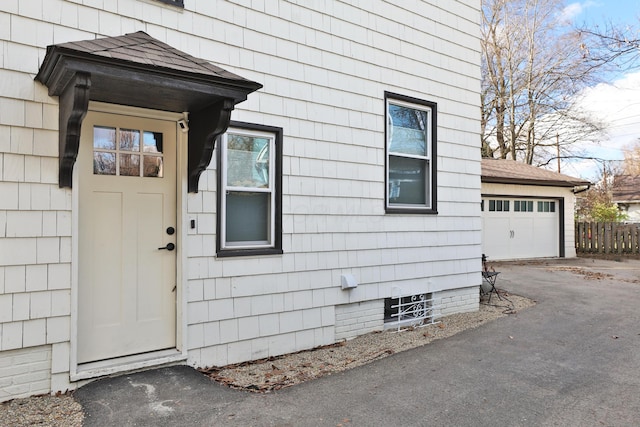 property entrance featuring an attached garage and fence