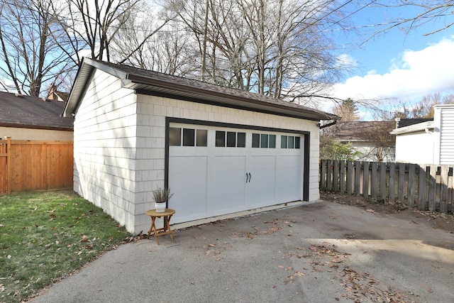 detached garage featuring fence and driveway