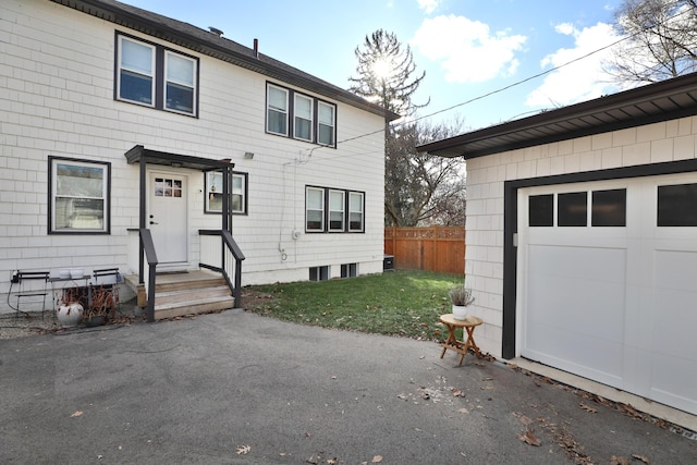 view of front of property featuring a garage, fence, and a front lawn