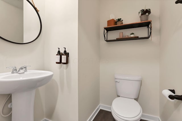 bathroom with baseboards, a sink, toilet, and wood finished floors