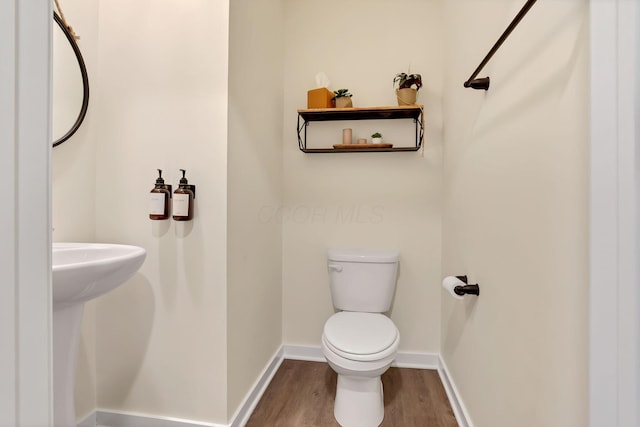 half bath featuring baseboards, toilet, and wood finished floors