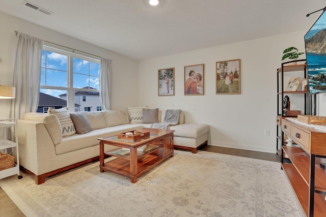 living room featuring visible vents, baseboards, and wood finished floors