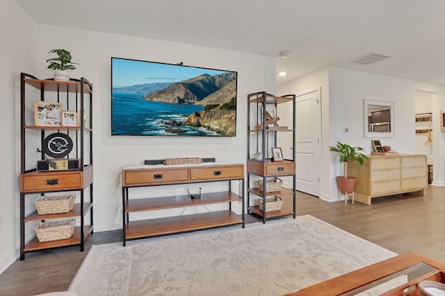 living area featuring baseboards, visible vents, and wood finished floors