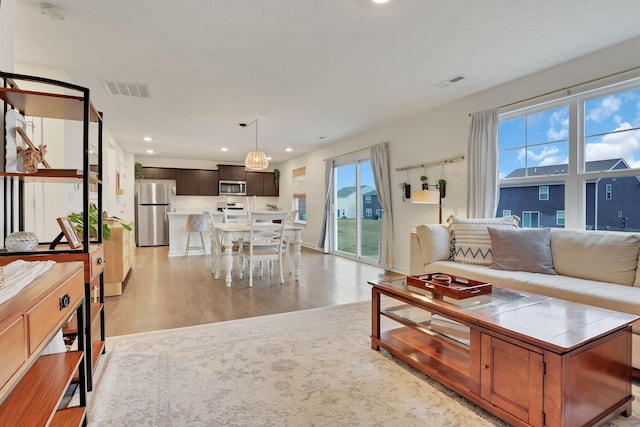 living area with light wood-type flooring, visible vents, and recessed lighting