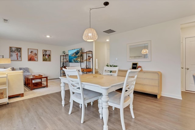 dining area with light wood-style floors, baseboards, and visible vents