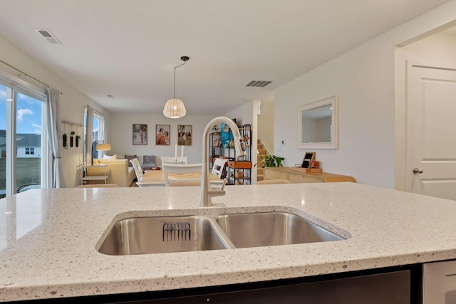 kitchen with open floor plan, a sink, visible vents, and light stone countertops