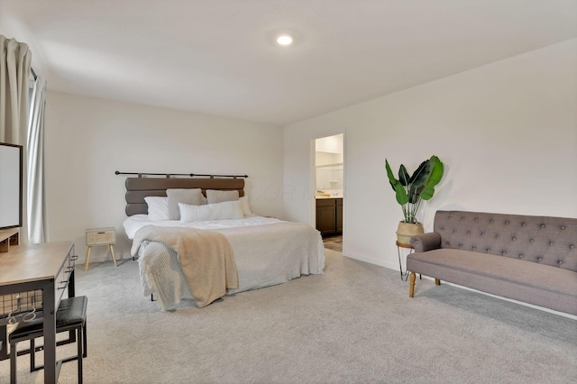 bedroom with baseboards, connected bathroom, and light colored carpet