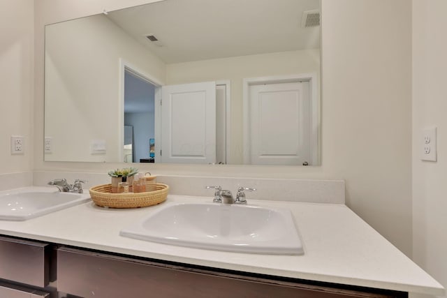 full bath with double vanity, a sink, and visible vents