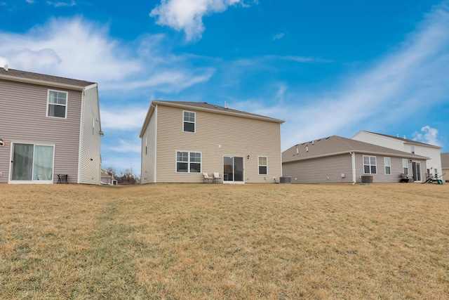 rear view of house with central AC and a yard