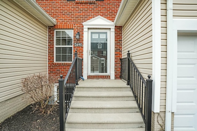 view of exterior entry with a garage and brick siding