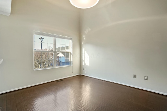 unfurnished room featuring wood finished floors, visible vents, and baseboards