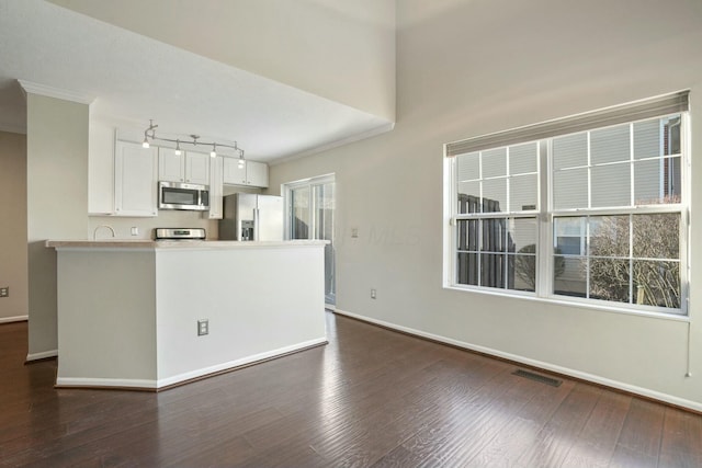 kitchen with visible vents, ornamental molding, stainless steel appliances, white cabinetry, and dark wood-style flooring