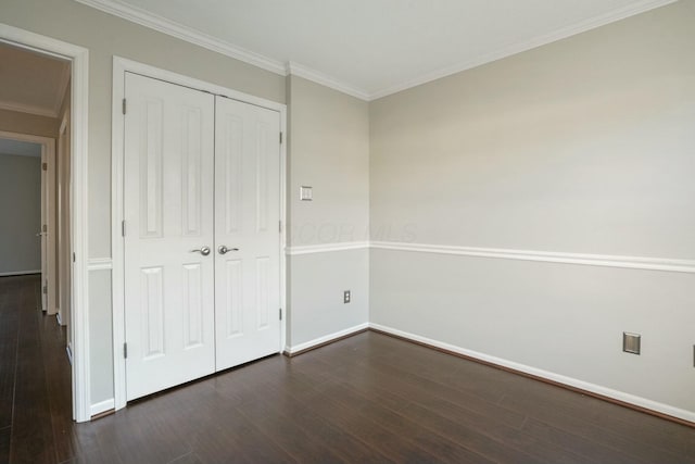 unfurnished bedroom featuring a closet, baseboards, dark wood-type flooring, and crown molding