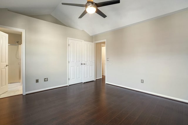 unfurnished bedroom featuring baseboards, vaulted ceiling, a closet, a ceiling fan, and dark wood-style flooring