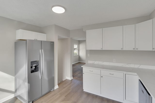 kitchen with a textured ceiling, white cabinetry, baseboards, appliances with stainless steel finishes, and light wood finished floors