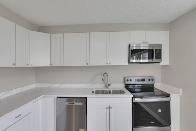 kitchen featuring white cabinets, appliances with stainless steel finishes, light stone countertops, a textured ceiling, and a sink